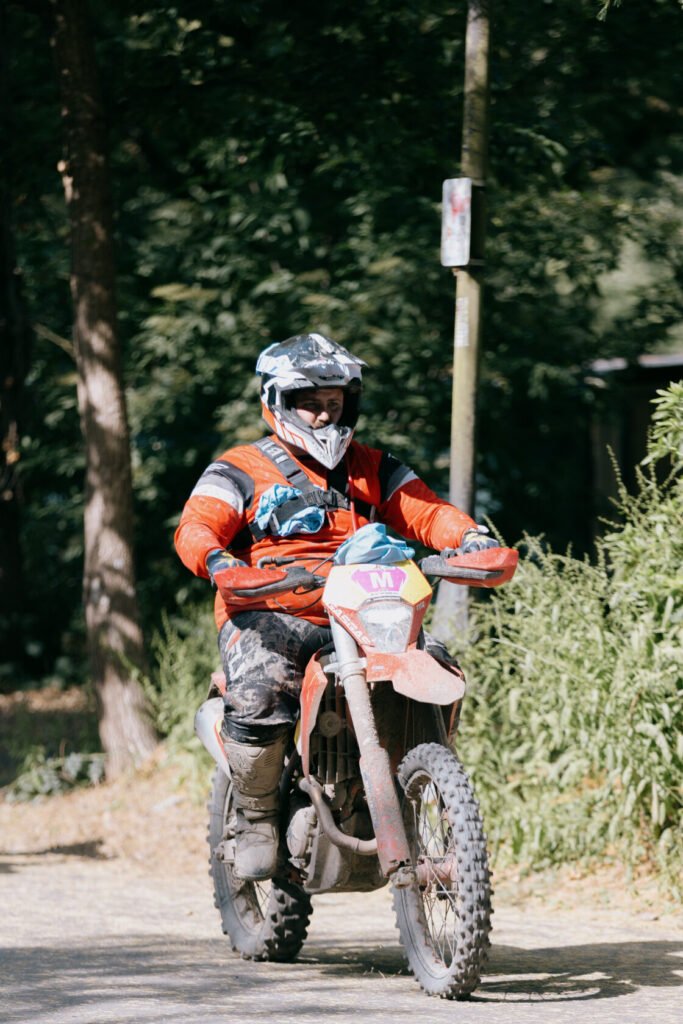 Motorcyclist in helmet and gear riding through leafy path.