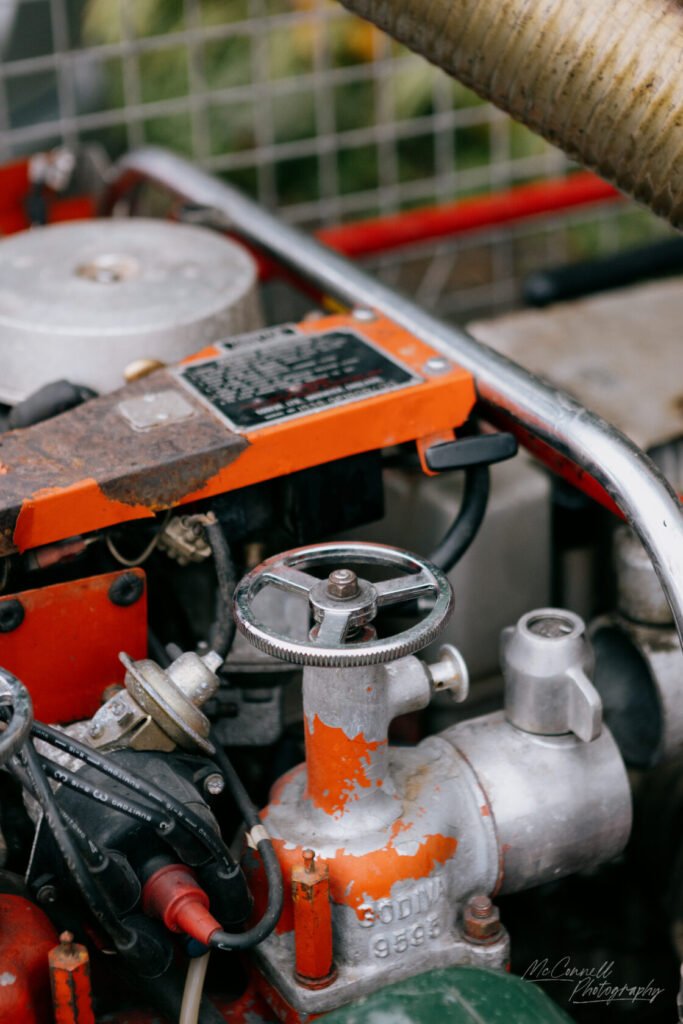 Detailed view of engine components with a rusty valve, silver parts, and colourful orange detailing.