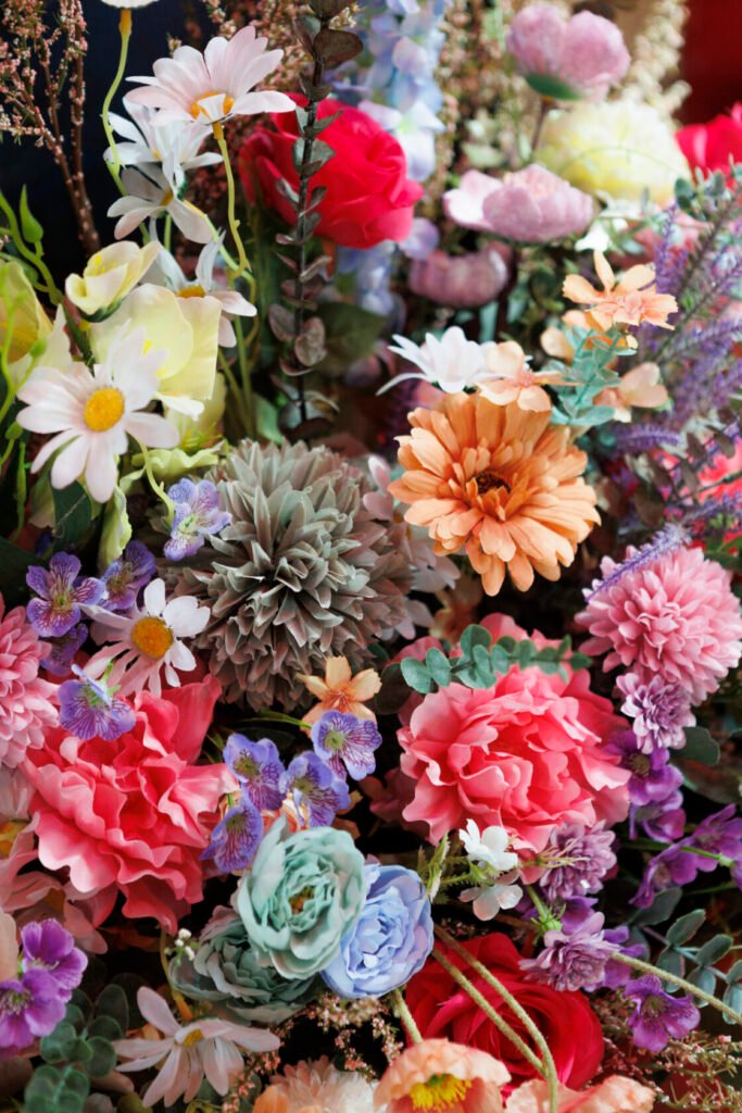 A colourful display of various artificial flowers, including daisies, roses, and peonies, in shades of pink, purple, and green. Shot for Lydia Turner.
