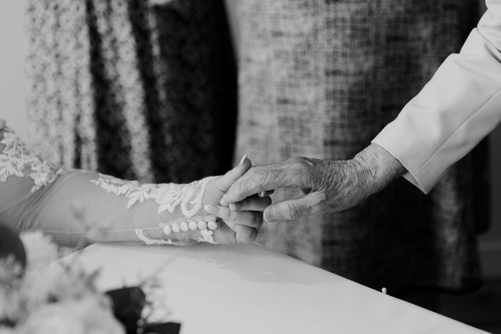 Touching Moment Between Generations A young woman's hand gently holds the hand of an older person, illustrating a moment of tenderness and connection.